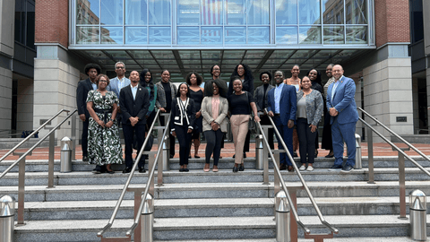 Diverse group of law students and faculty standing on courthouse steps beneath a glass walkway.”